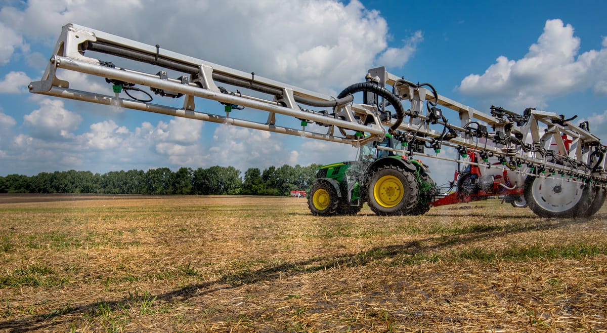 Modern szántóföldi permetezőgép munka közben egy tarlón, precíziós mezőgazdasági technológiával.